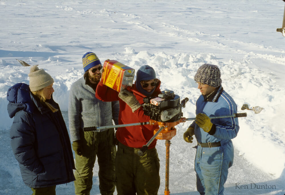 Refueling powerhhead during ice hole drilling in winter 1979. L to R, Susan Schonberg, Jim Hanes, Gene Cinkovich, and John Olson